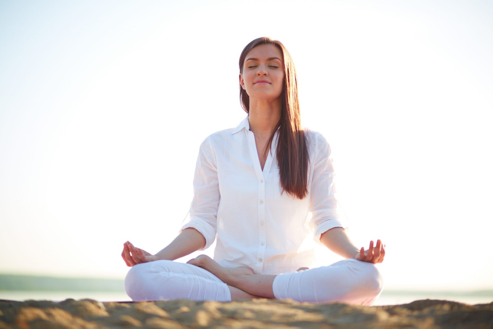 Meditating woman sitting in pose of lotus against clear sky outdoors